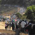 a larege group of pilgrims in line walking through wooden, hilly country